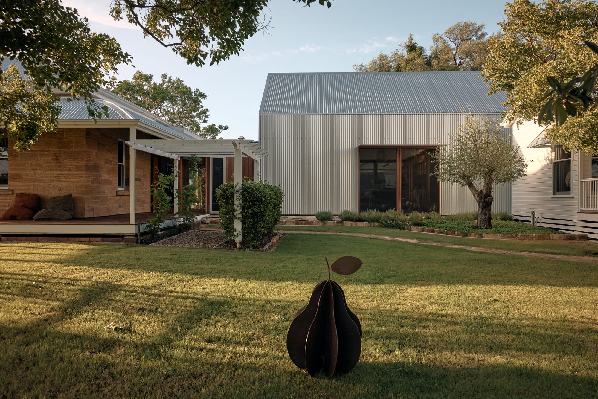 Heritage-style home and contemporary corrugated metal addition arranged around a landscaped garden and lawn.