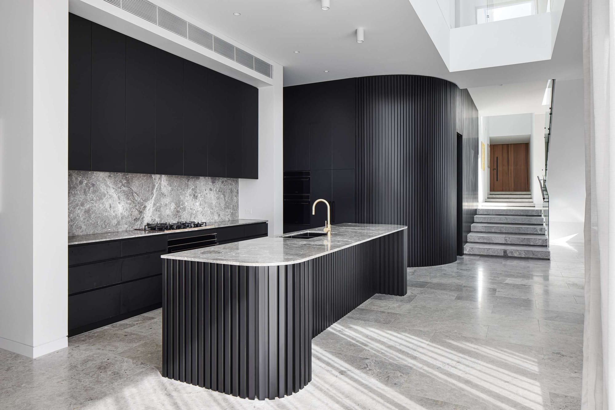 Black fluted kitchen joinery with natural light falling from a nearby stairwell skylight