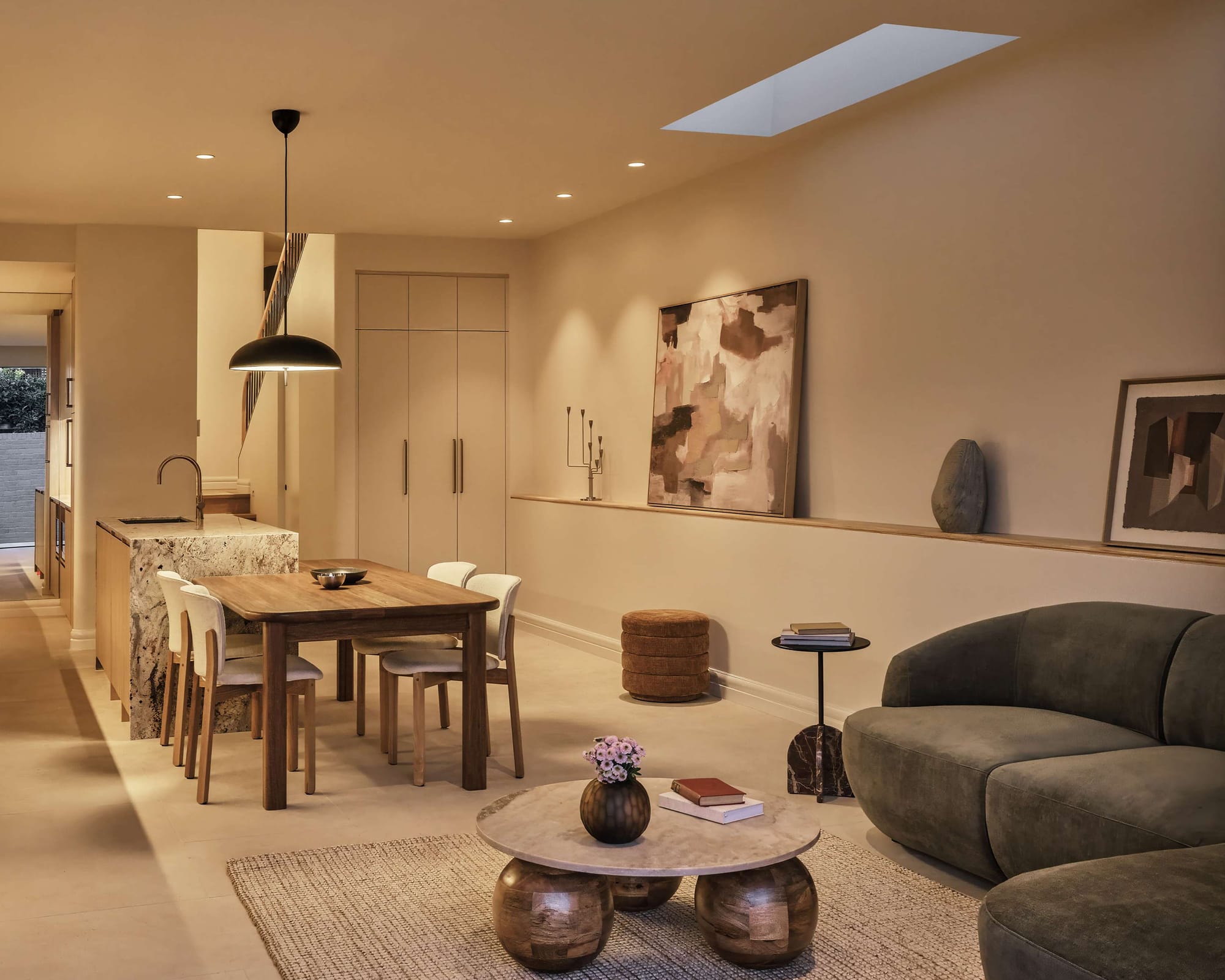 Dining area lit by a single angled skylight beside a sculptural spiral staircase, Arco House by Jose Chandia Interiors