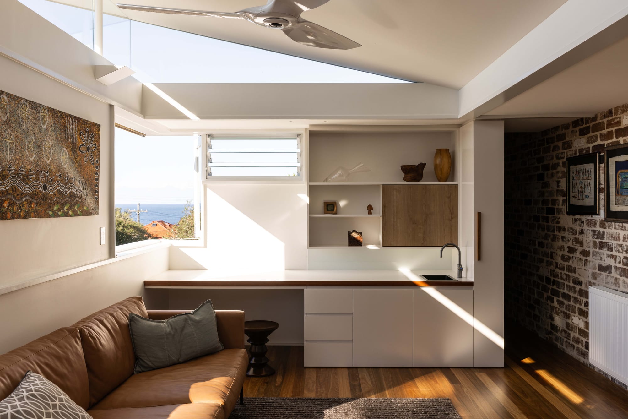 Angled skylight above a living space with exposed recycled brick wall and ocean views