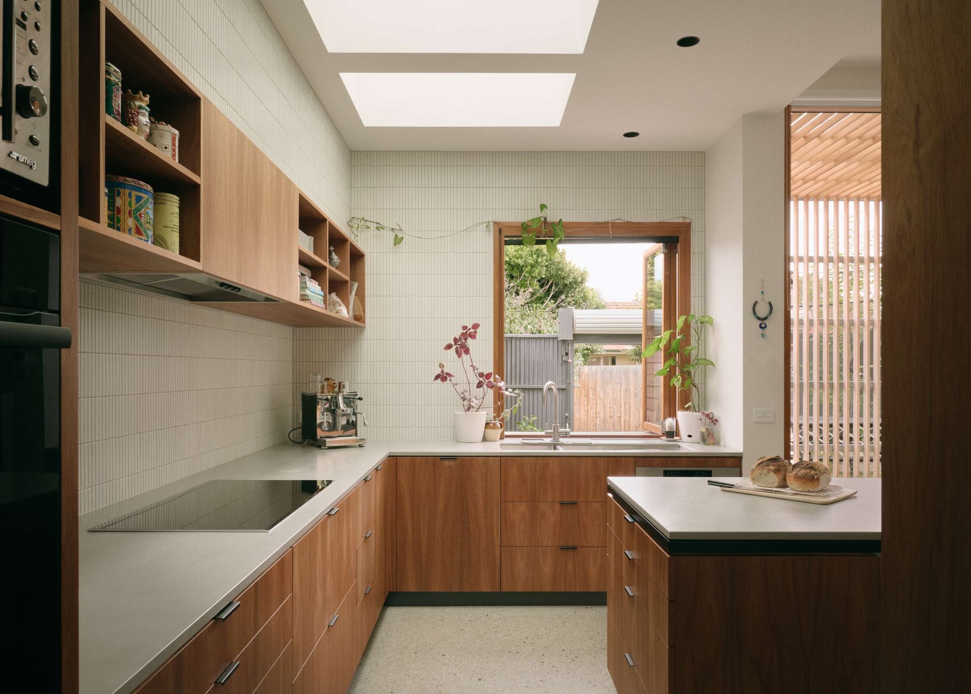 Timber kitchen with U-shaped cabinetry, open shelving, skylights and a window overlooking the garden.