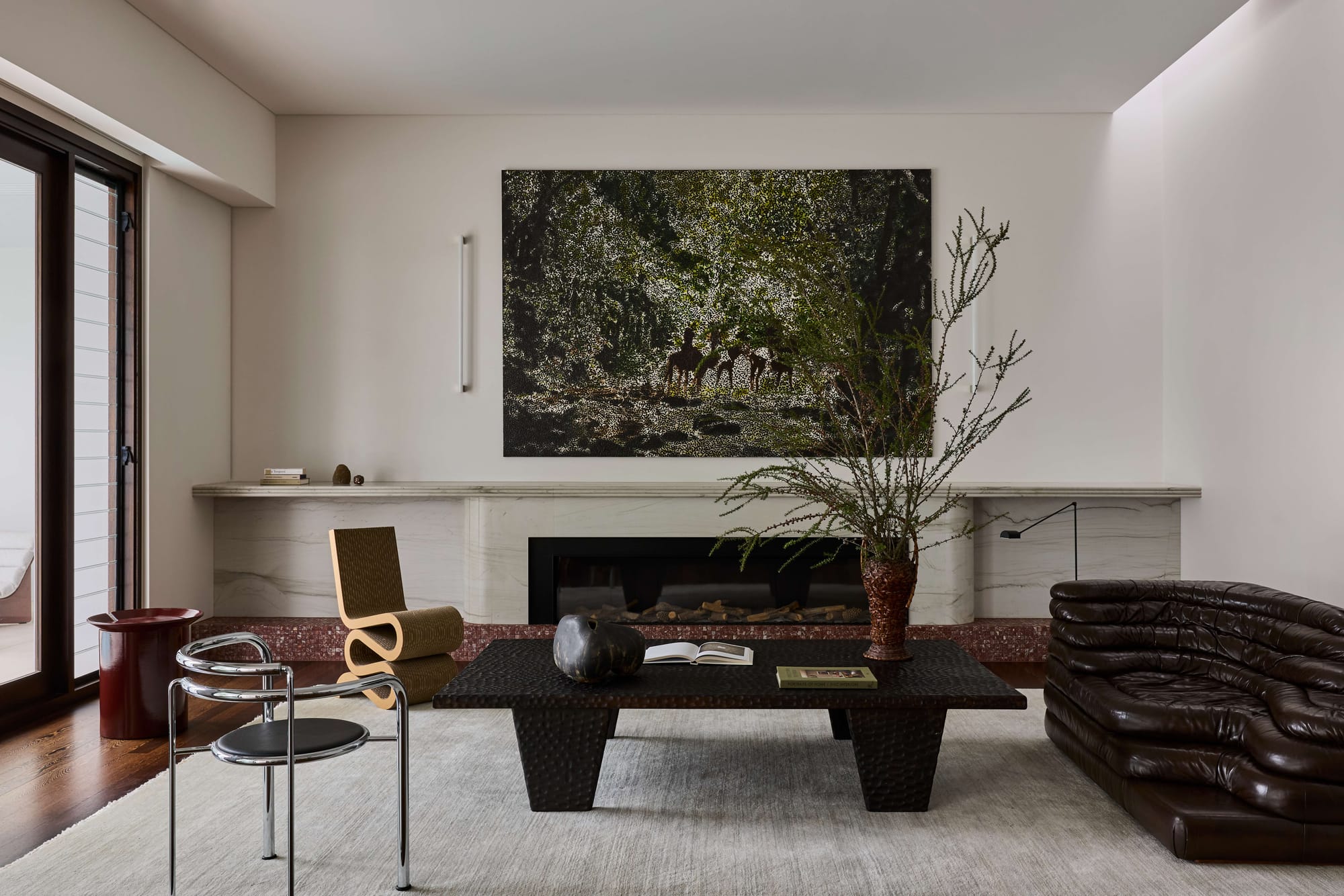 Living room at Rose Bay Residence by Studio PULP with a stone fireplace, sculptural furniture, dark timber flooring and large artwork above the mantel.