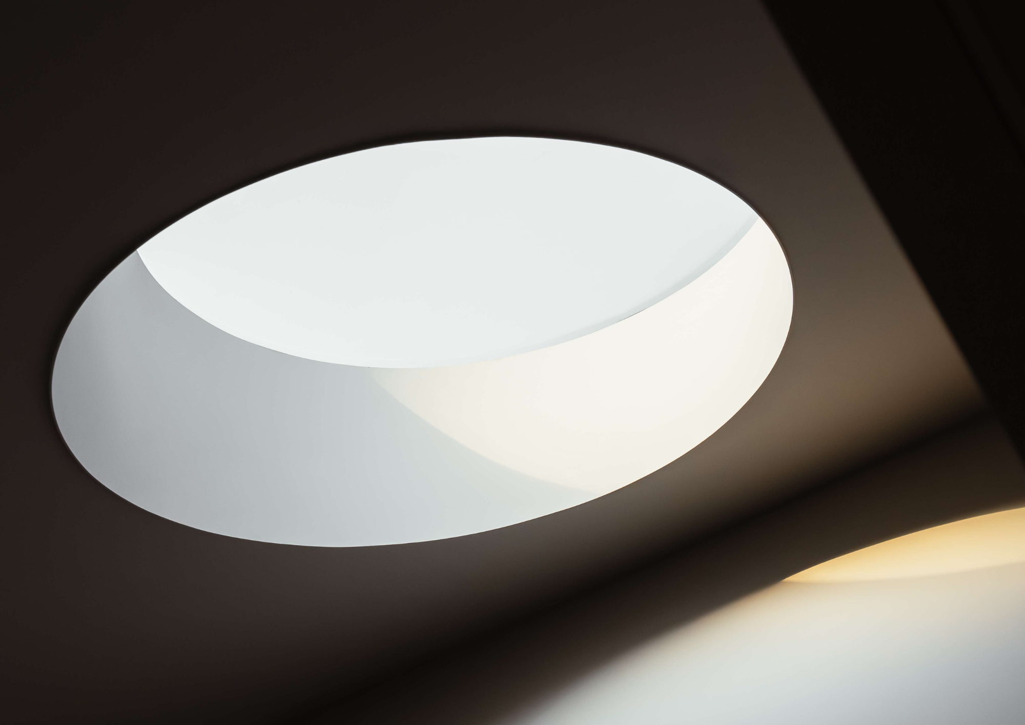 Close-up of a round recessed skylight glowing softly against a dark ceiling, Malvern by Kairos Design Studio
