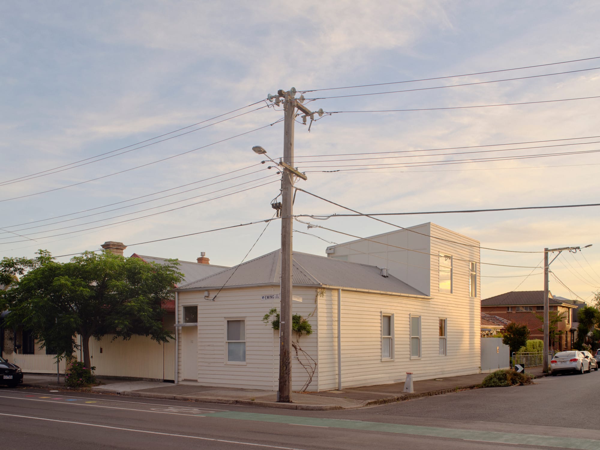 Street view of Brunswick Corner House by Office Fora, showing the original weatherboard cottage and contemporary upper-level extension on the corner site.