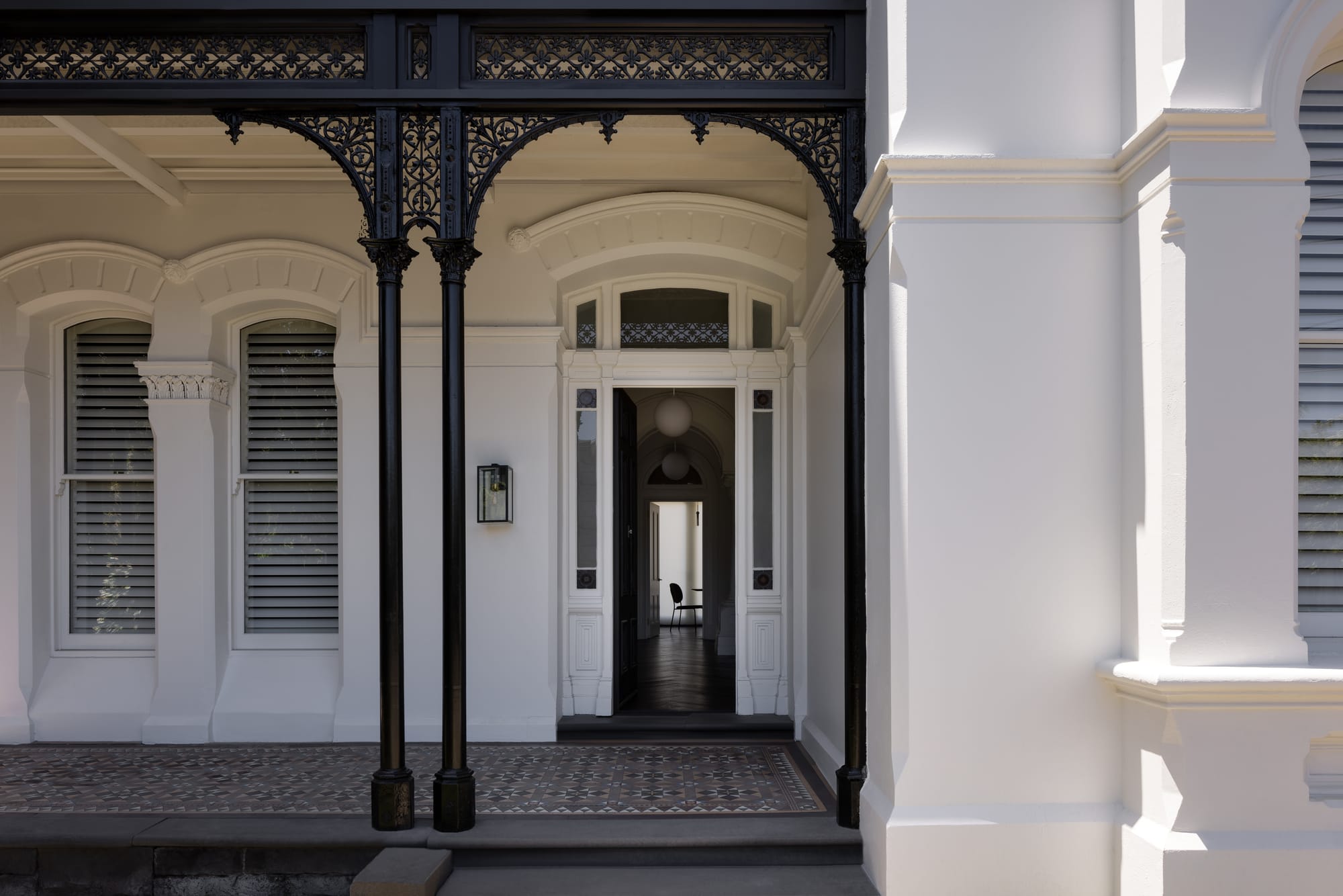 Restored entrance to Beverley Residence by By Mysa with ornate black ironwork, arched openings, shuttered windows and patterned verandah tiles.