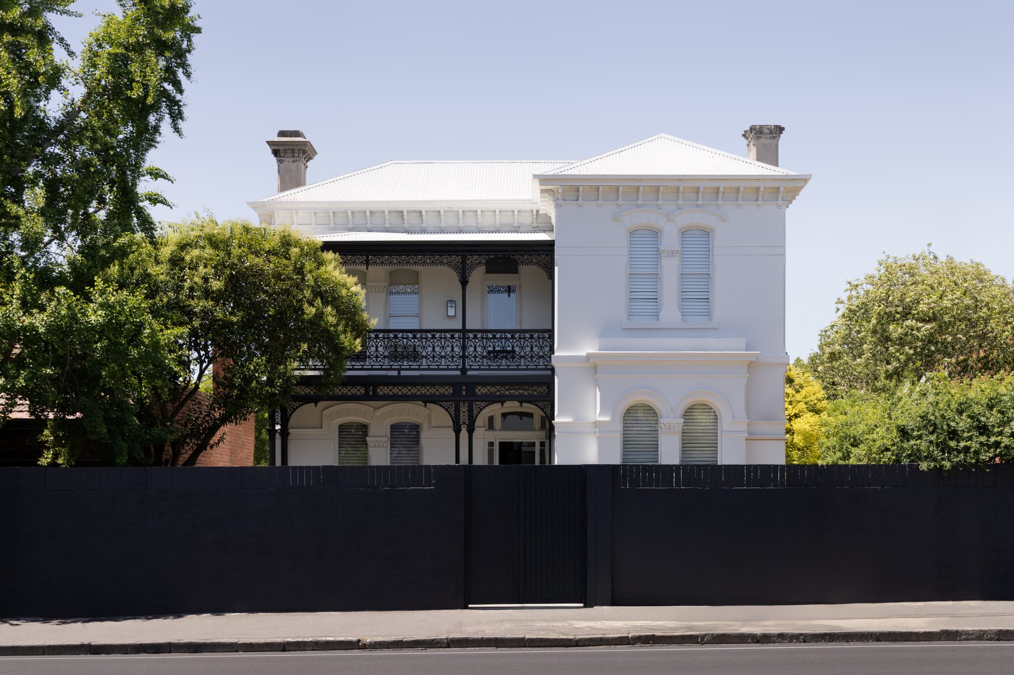 Restored white Italianate Victorian facade at Beverley Residence by By Mysa, with ornate ironwork, shuttered windows and a dark front fence.
