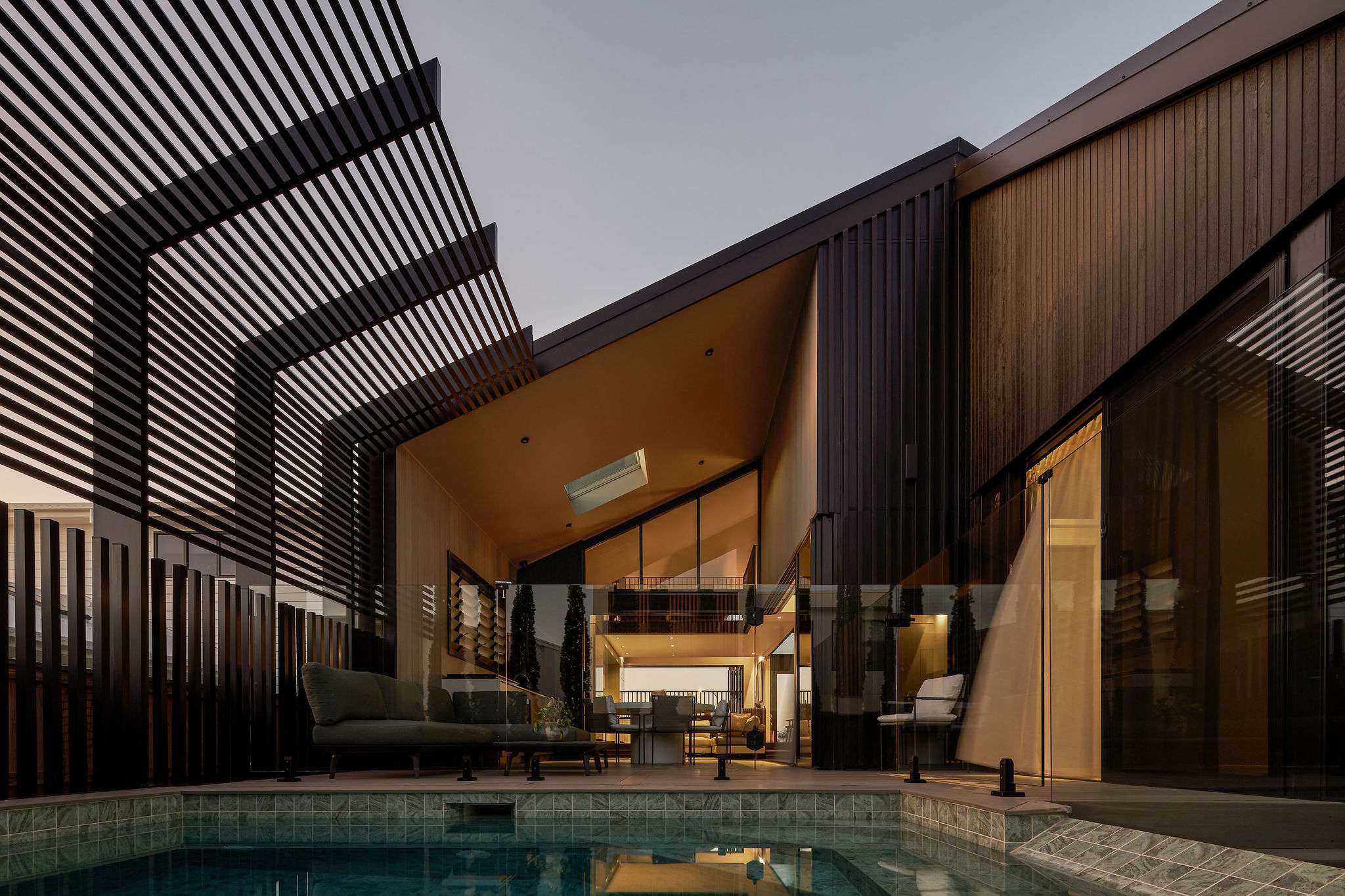 Contemporary courtyard and pool framed by timber cladding, large glazing and a slatted overhead screen at Middle Habitat. Photography by Andy Macpherson Studio.