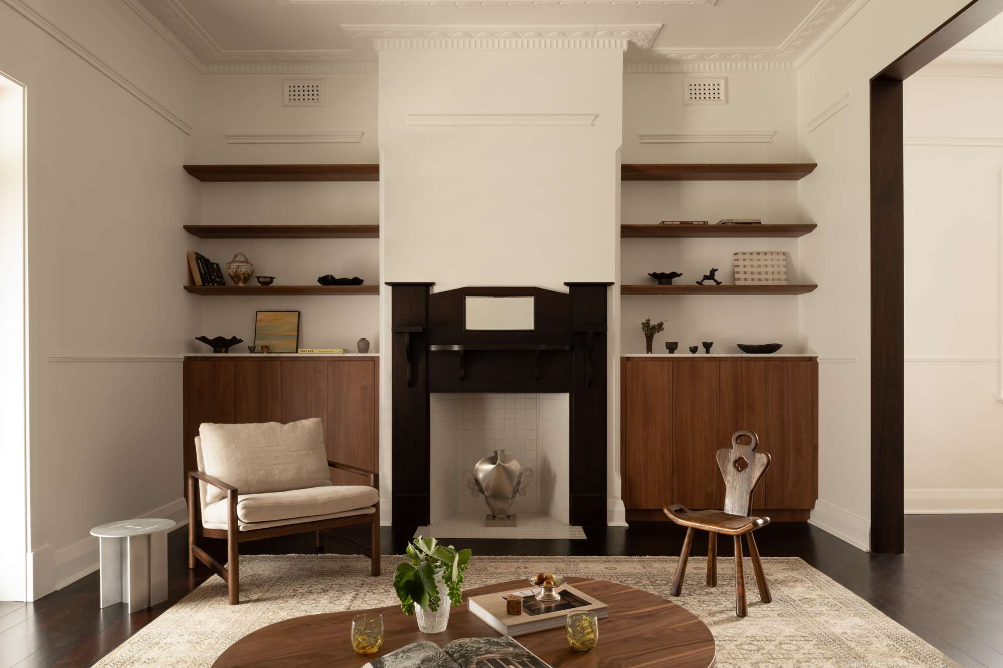 Living room at Oakover by Amass Architects with restored period detailing, dark timber fireplace, built-in cabinetry and warm timber furniture.