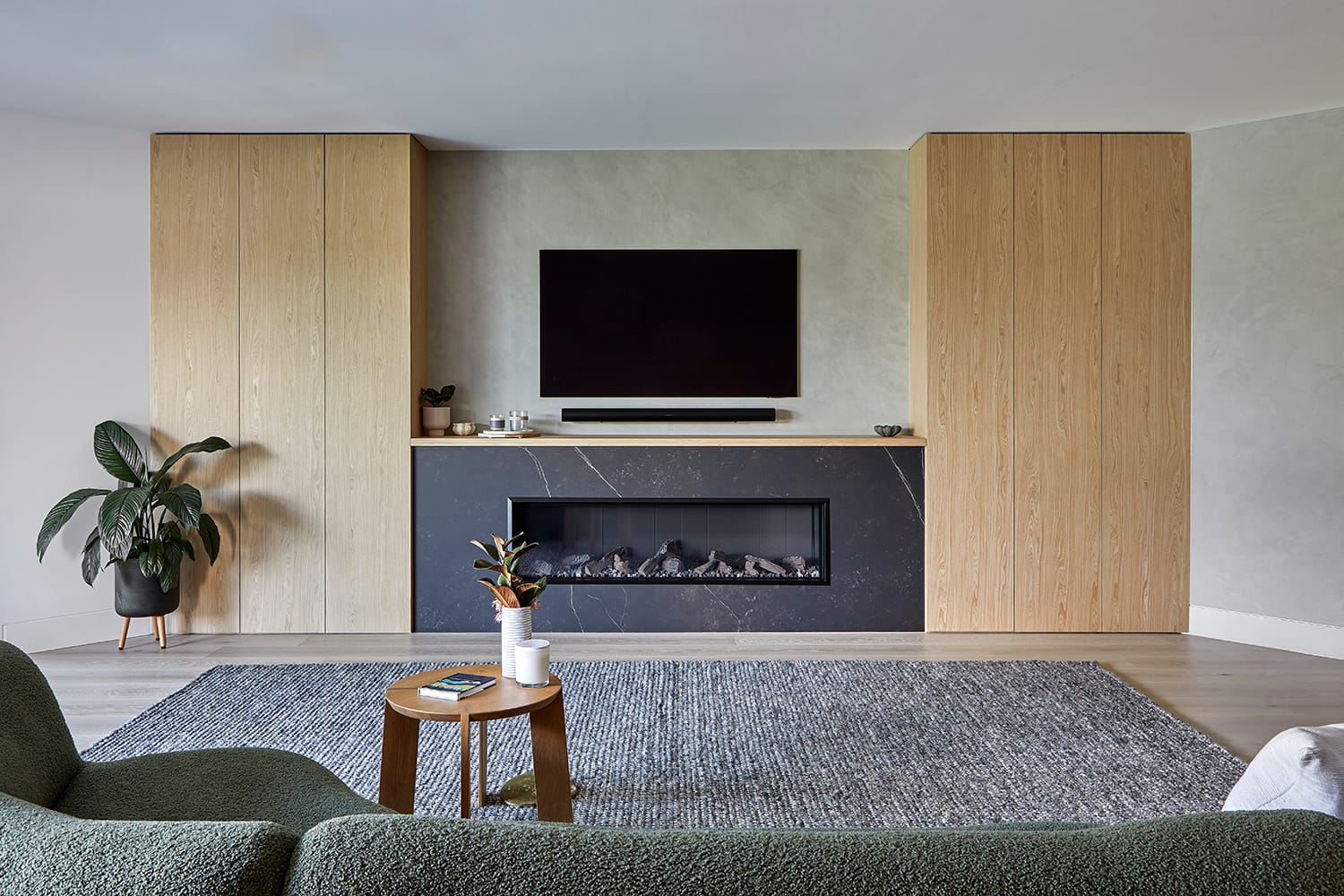 Open-plan kitchen and living space with timber wall panelling, marble island bench, exposed brick detailing and copper pendant lights beneath a skylit ceiling.