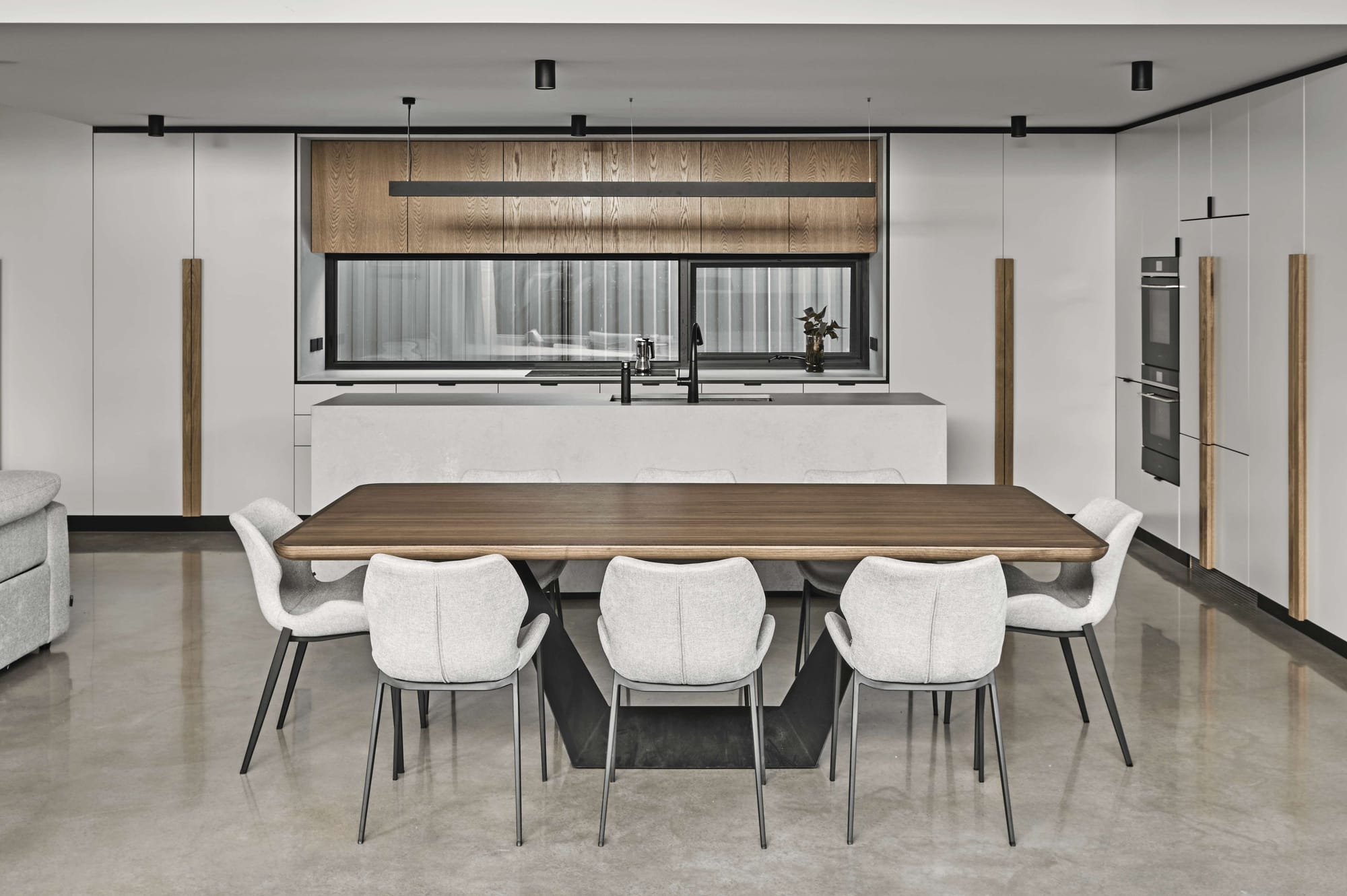 Contemporary two-storey home with black metal cladding, white brick screening and a timber garage door.
