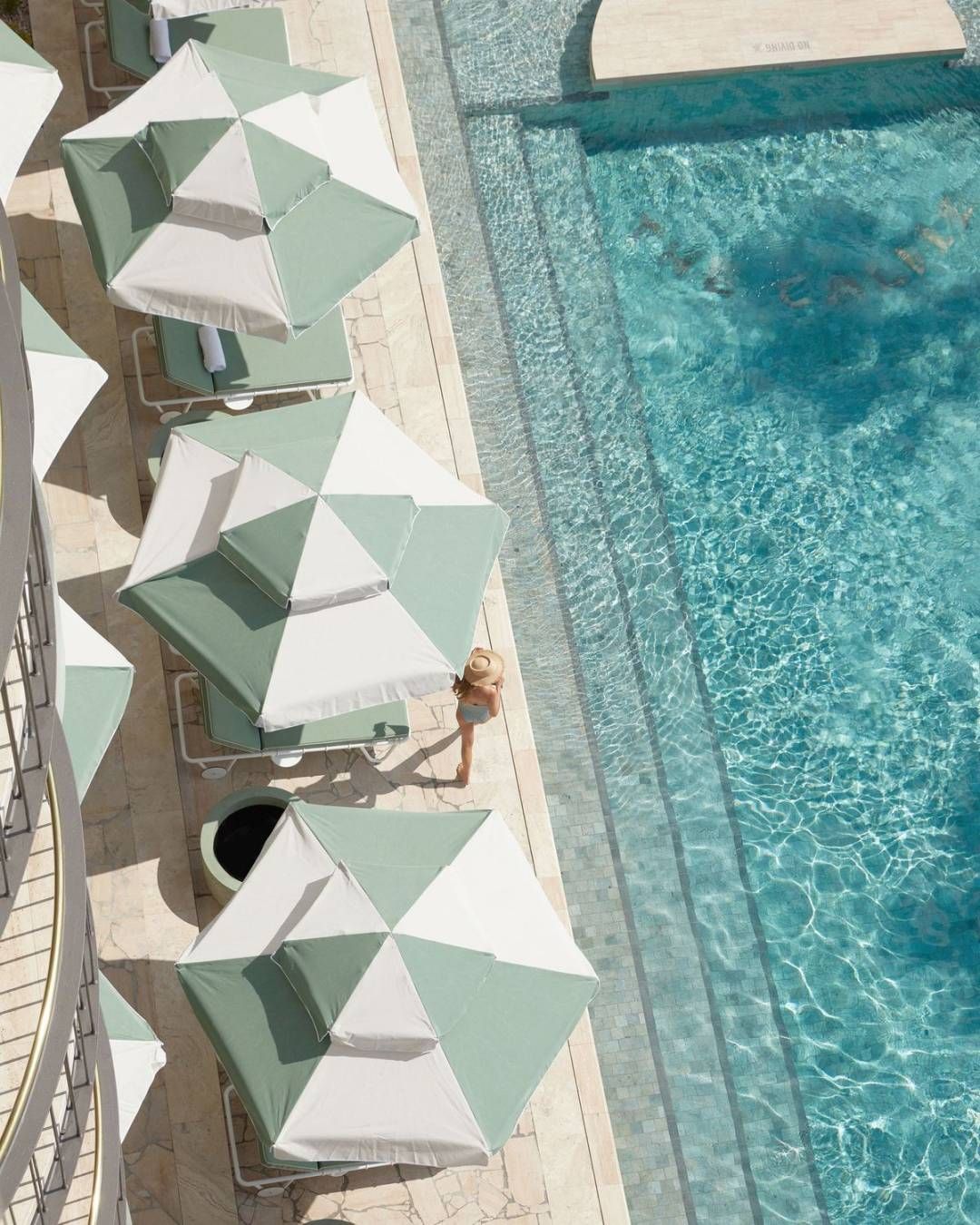 The Calilie Hotel poolside with green and white umbrellas and sun loungers