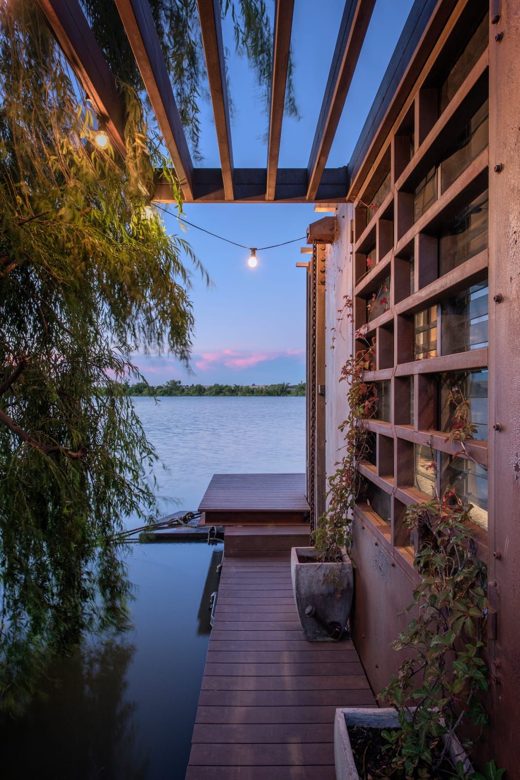 Bill's Boathouse. An exterior view of the houseboat showing the timber deck and view of the river beyond