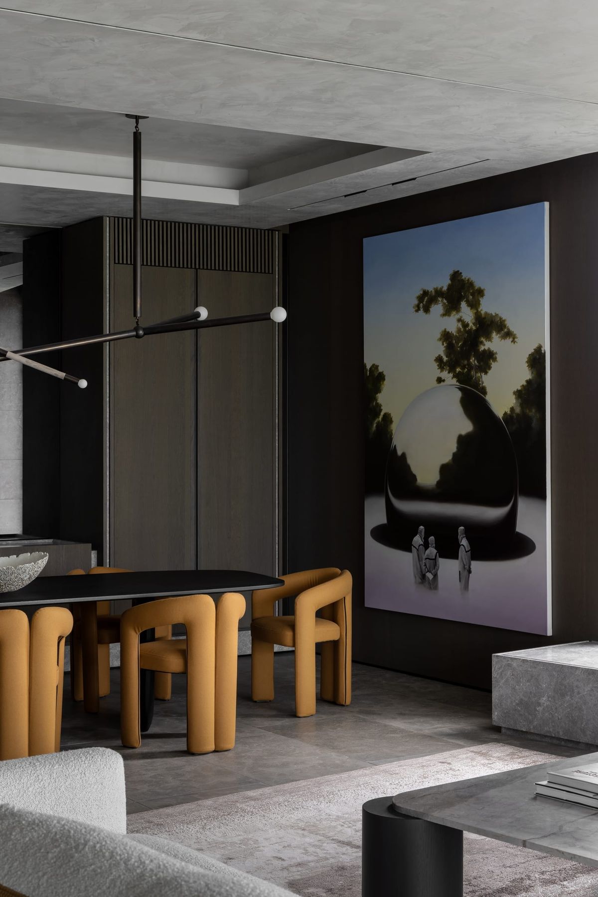 Black dining table with muted orange chairs. Stone floors. Timber cabinetry in background. 