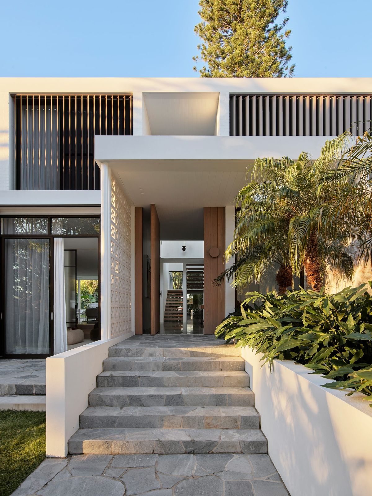 Entry to Warren House by CM Studio showing the stone paved steps and large front timber door