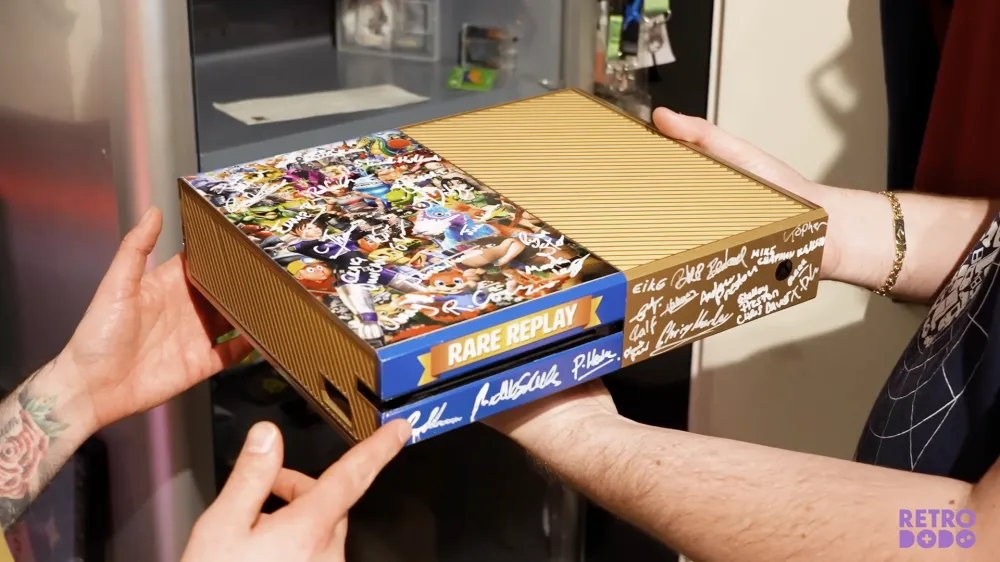 A golden Xbox One with Rare game characters and signatures of the Rare developer team