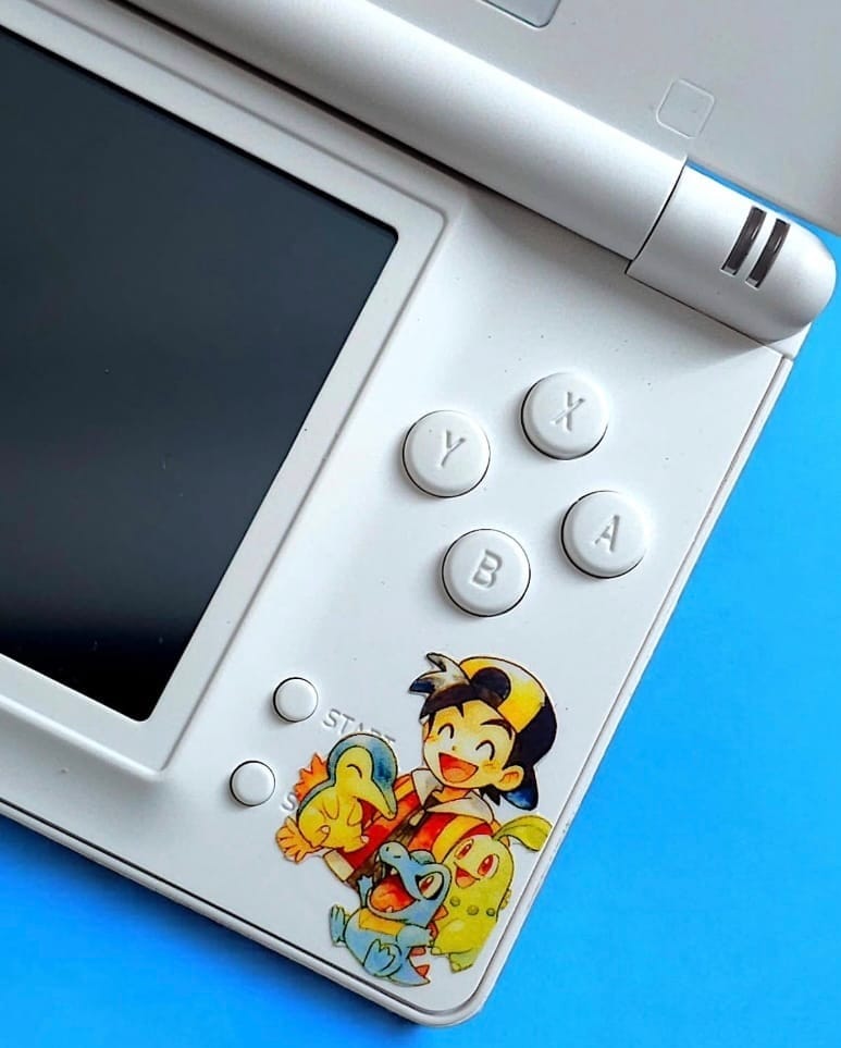A Pokémon Trainer decal on a white DS Lite