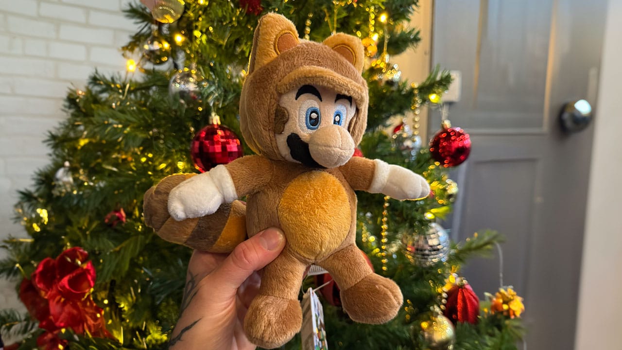 Seb holding a Tanooki Mario Plush by a Christmas tree