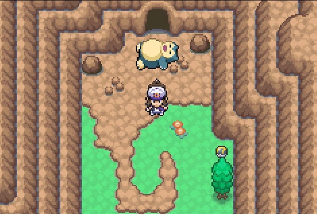 Pokémon trainer by a sleeping Snorlax, who is blocking a cave