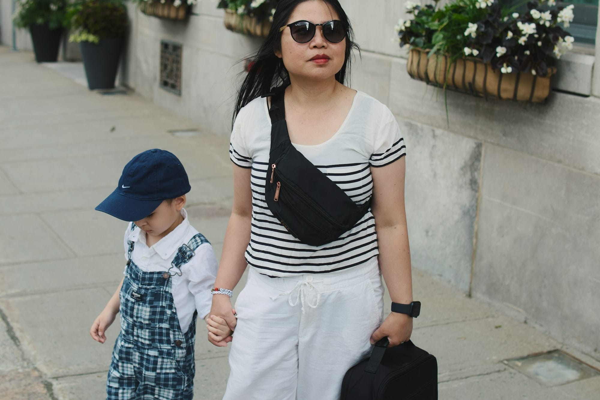 Woman and child walk hand in hand outdoors.