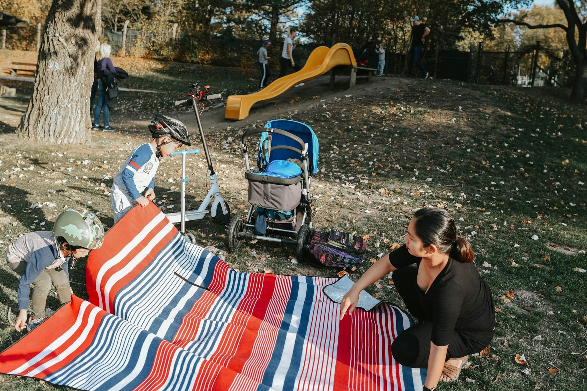 a group of people setting up a blanket in a park