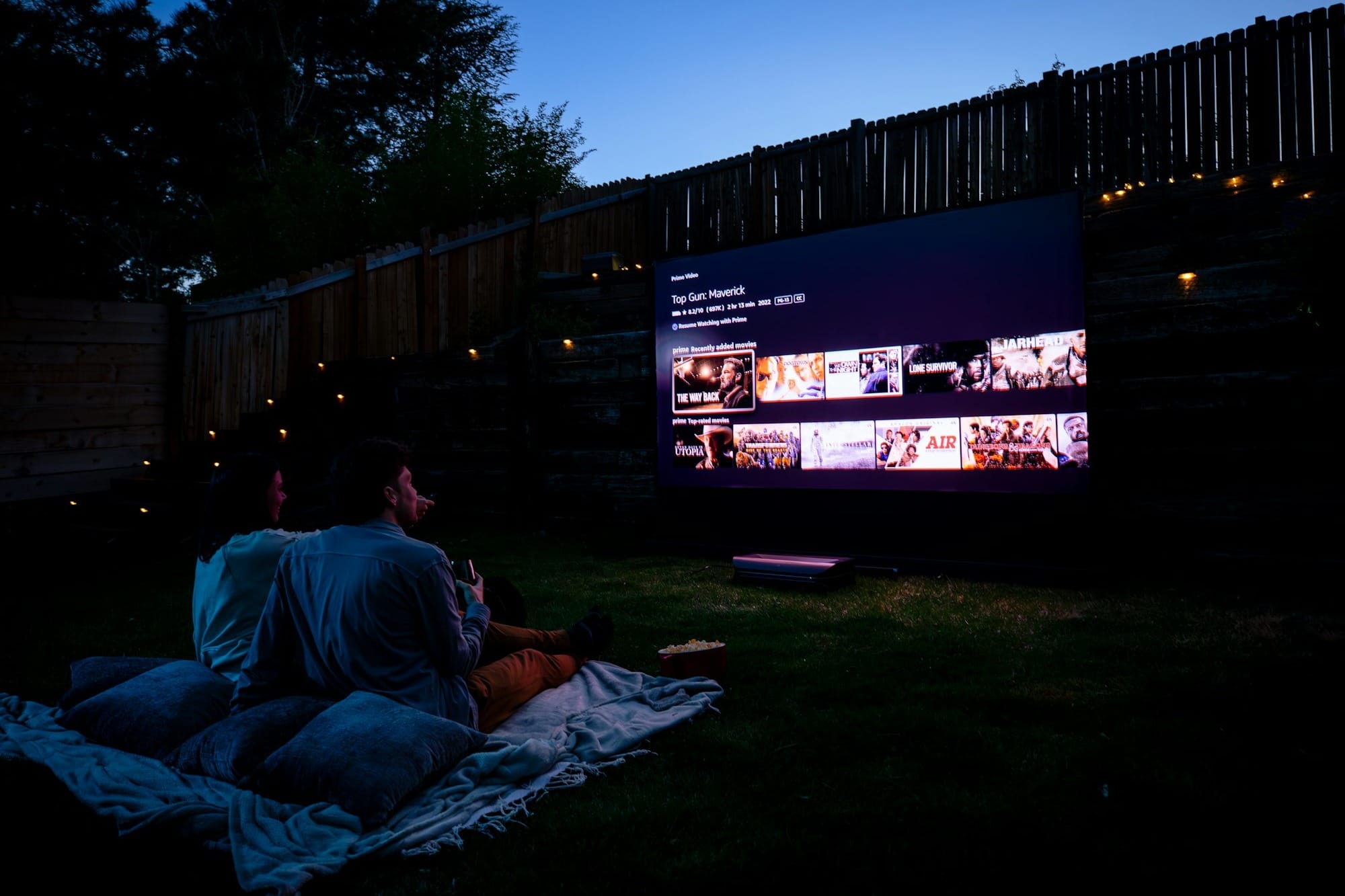 Two people sitting on a blanket watching a movie