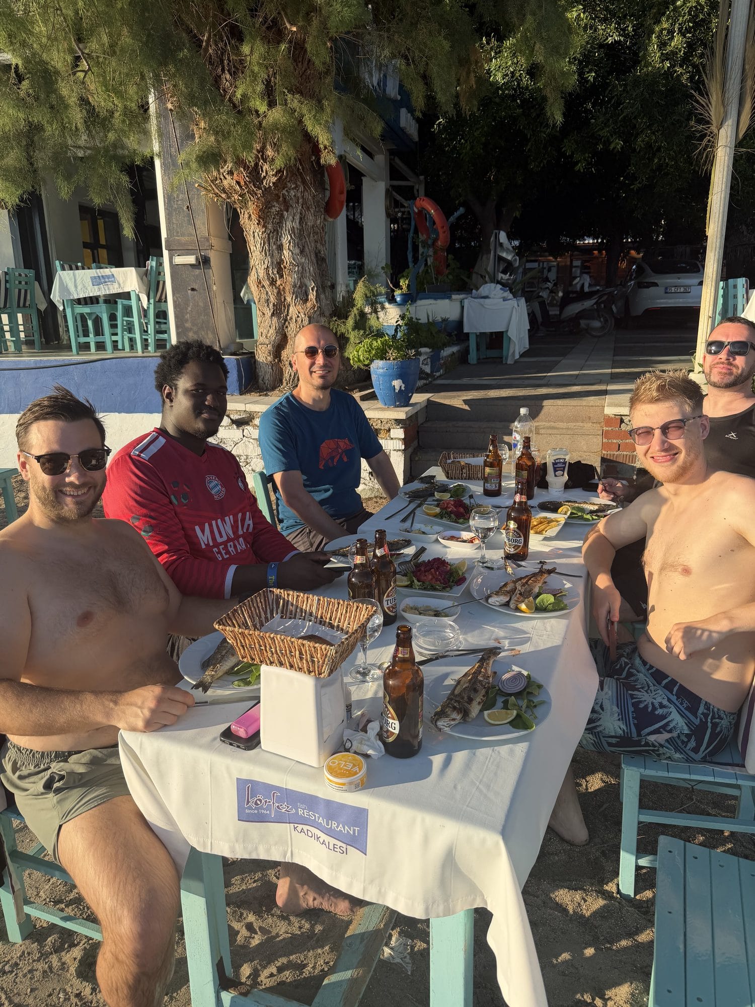 The team around a table of grilled fish and beers at a beachside restaurant
