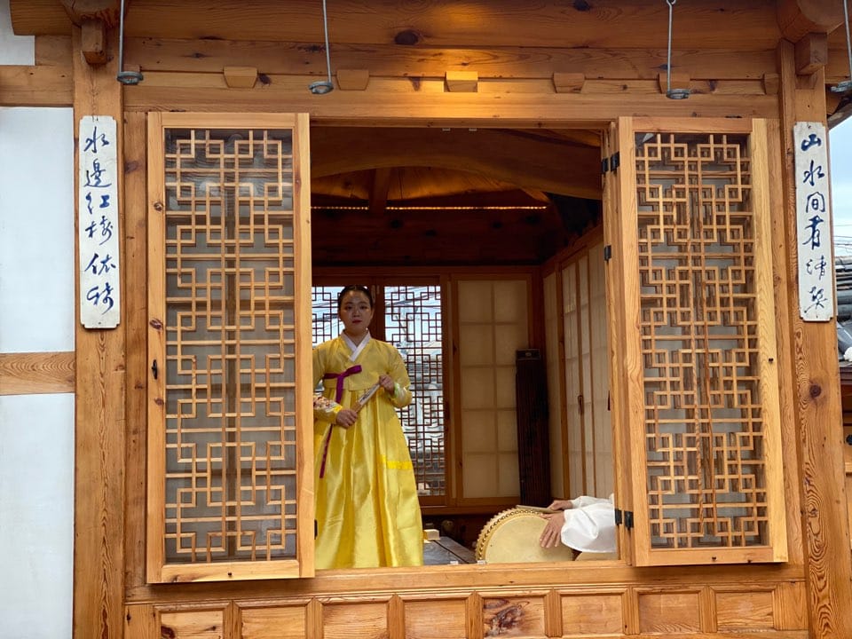 RakkojaeSeoul_CreditRakkojaeSeoul_GirlInWindow Frau im gelben Hanbok mit traditioneller Trommel