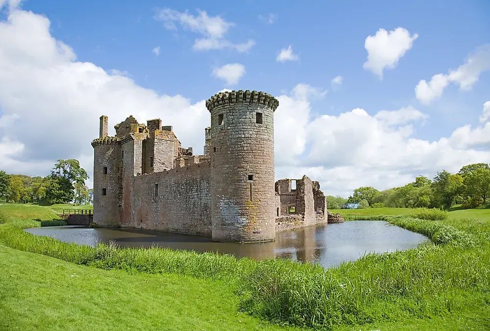 an image of a small medieval castle surrounded by a water filled moat