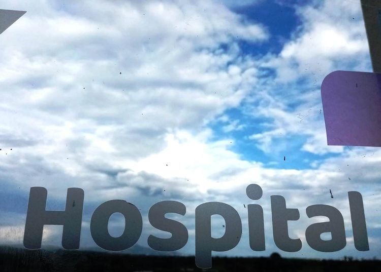 A partly cloudy sky through a hospital window. 