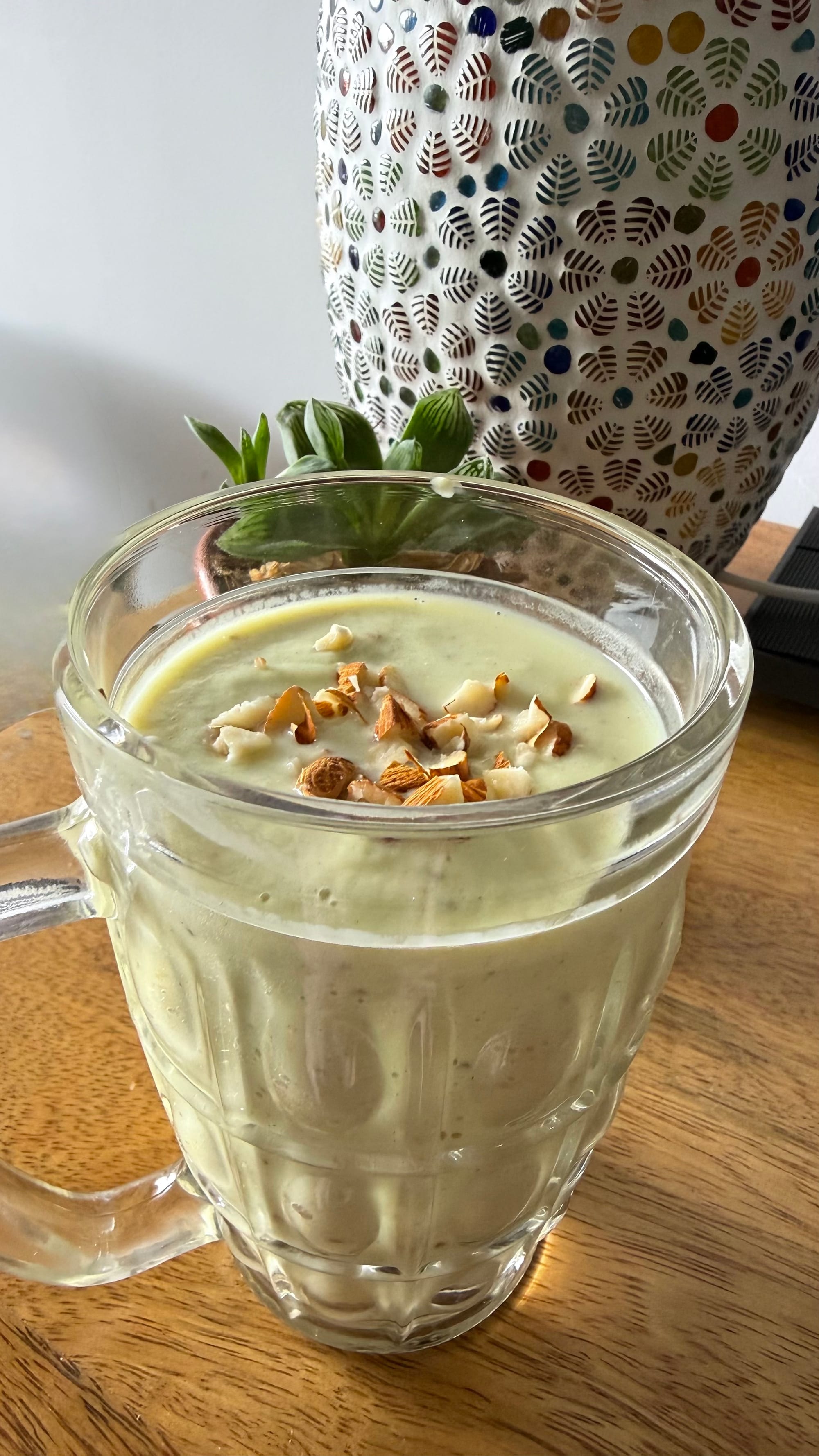 Avocado date smoothie in glass mug with crushed almond topping. Greek yogurt avocado dates blended smoothie recipe by Shradha Fuel It Right