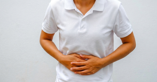Person holding stomach with both hands indicating acidity or gut discomfort