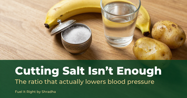 Photorealistic overhead photo of a small dabba of salt beside a banana, coconut water, and boiled potatoes, with headline "Cutting Salt Isn't Enough" for the Fuel It Right blog