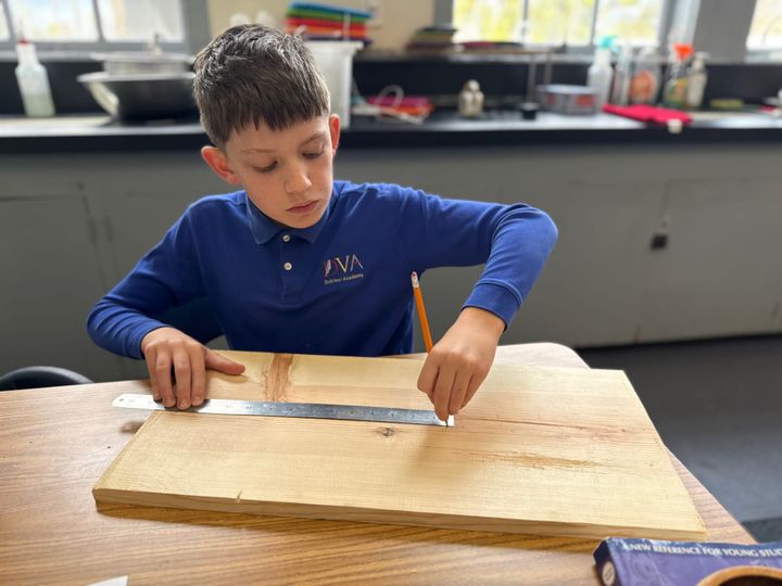 Male fourth grade student using ruler on wood for STEM project