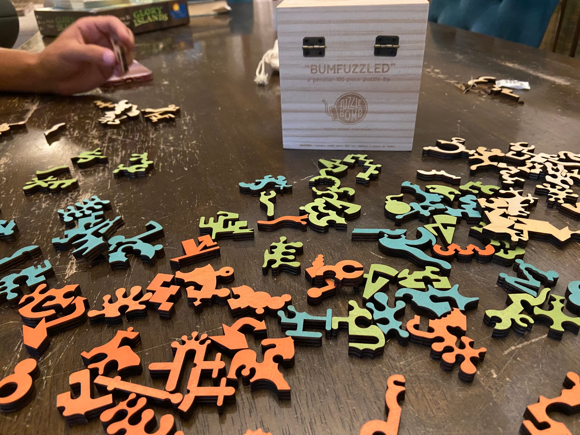 The 100 funky wooden pieces of a jigsaw puzzle are scattered on a wood table