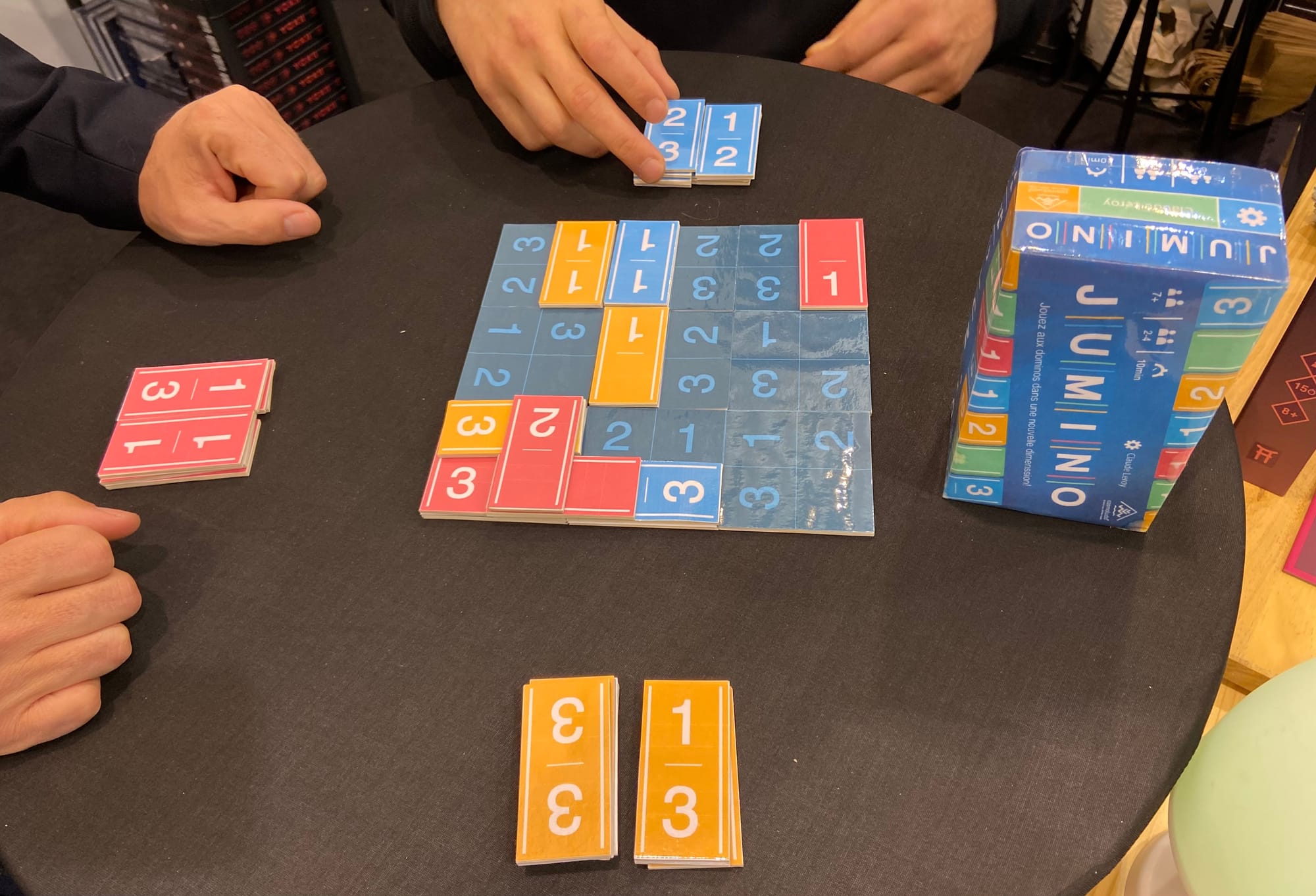 Three colors of domino-style tiles are being placed in a 6x6 grid, with the components clearly being mock-ups