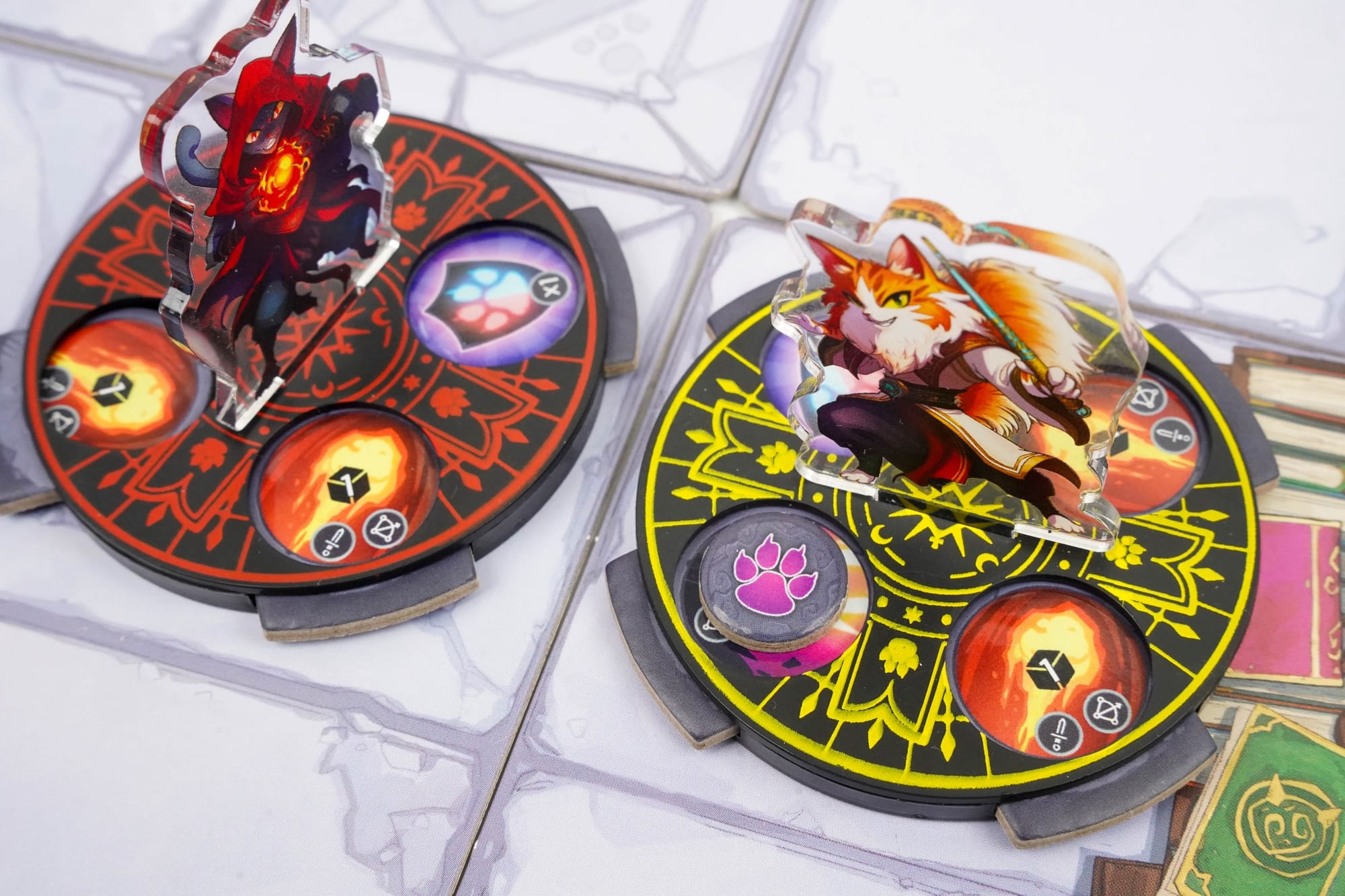 Two cat wizards stand on displays that each contain four magic tokens