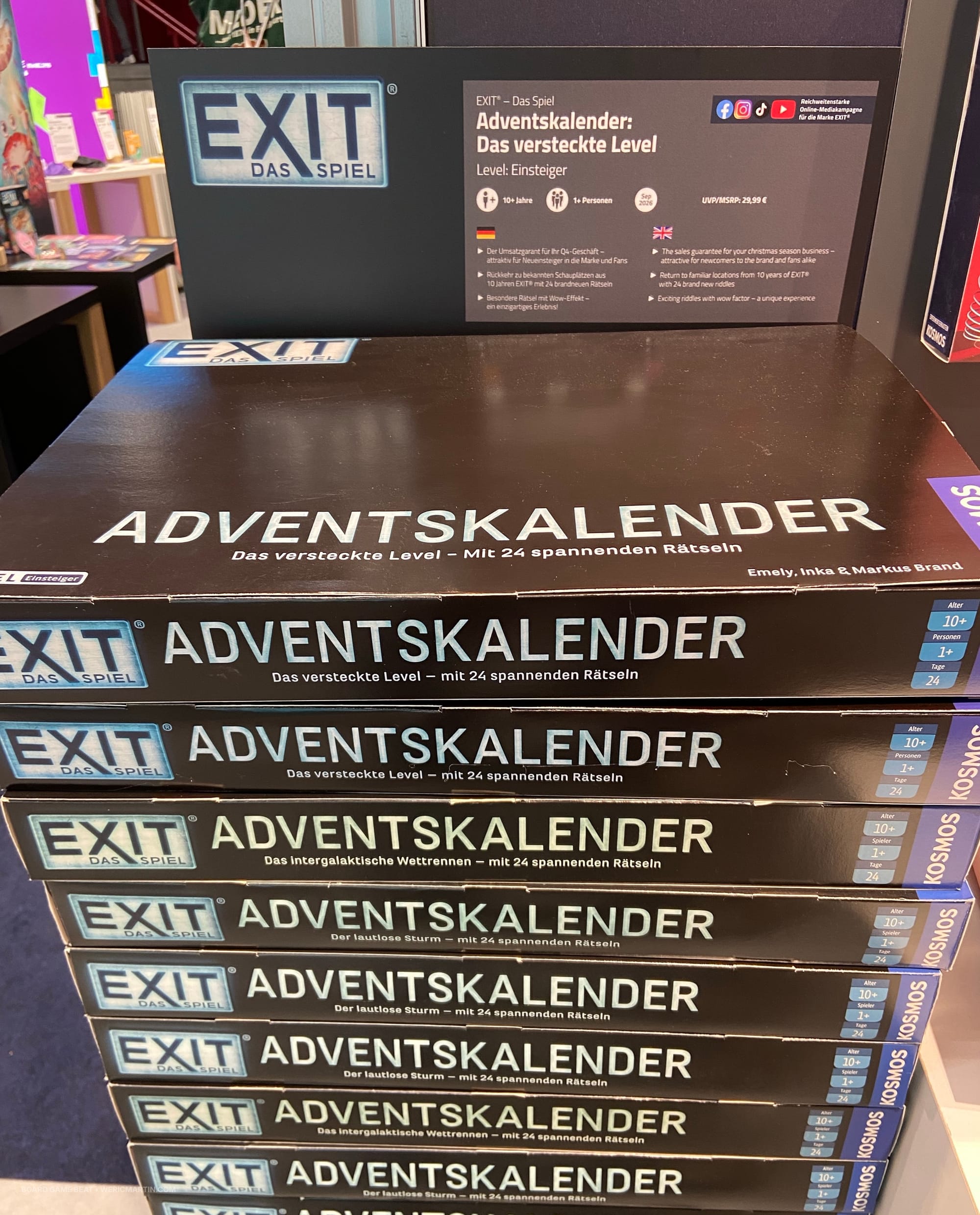 A stack of boxes labeled EXIT: Das Spiel – Adventskalender – Der versteckte Level that are all black, revealing no info on the cover