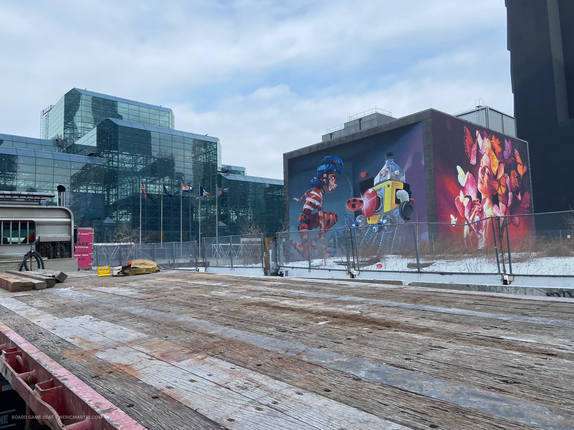 The glass structure of the Jacob K. Javits Convention Center is on the left of the image, while the right shows characters from the Miraculous anime series, as well as a woman surrounded by butterflies
