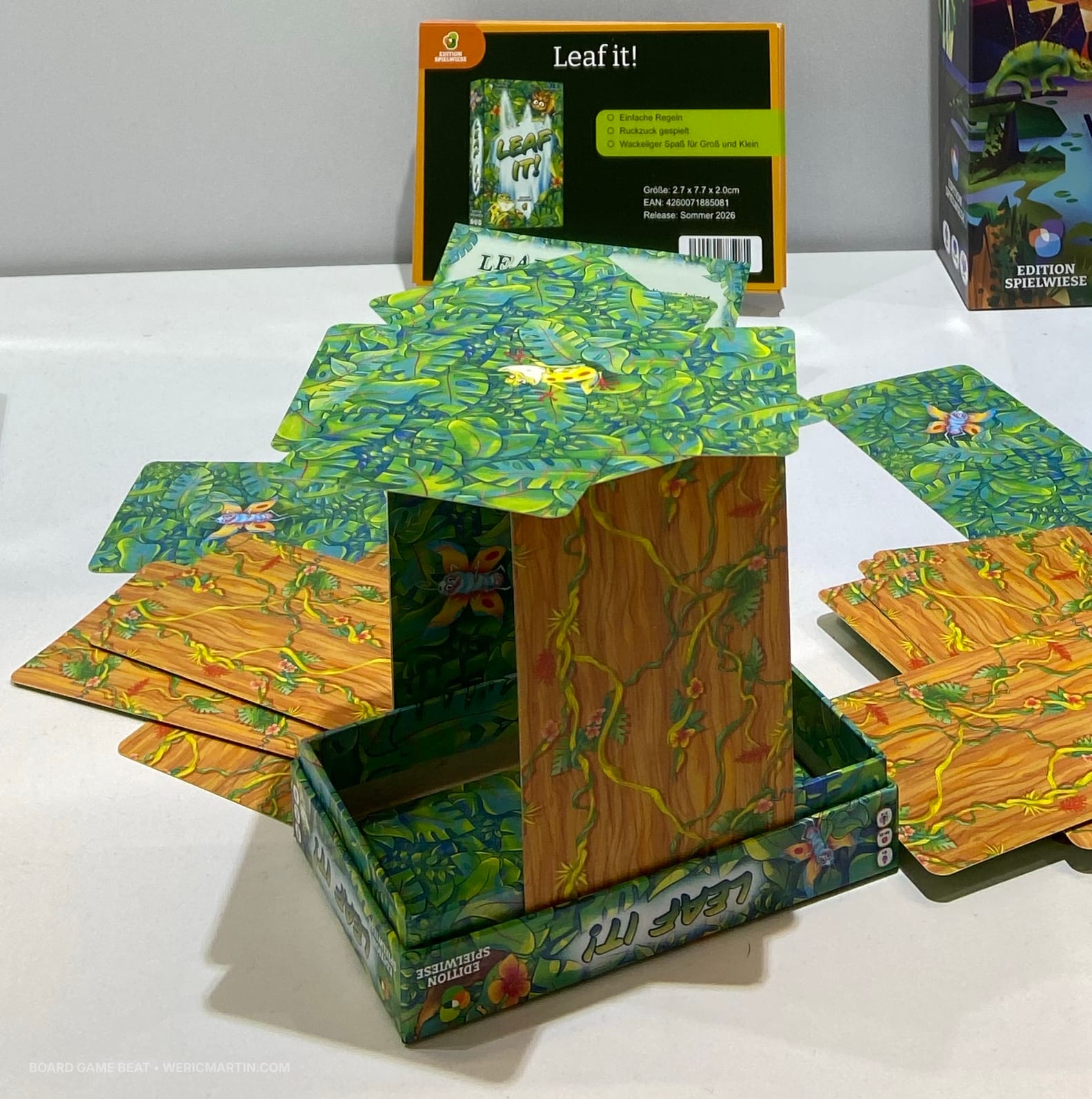 Cards are stacked on two vertical cards stuck inside nested box lids, thereby forming a tree with a canopy