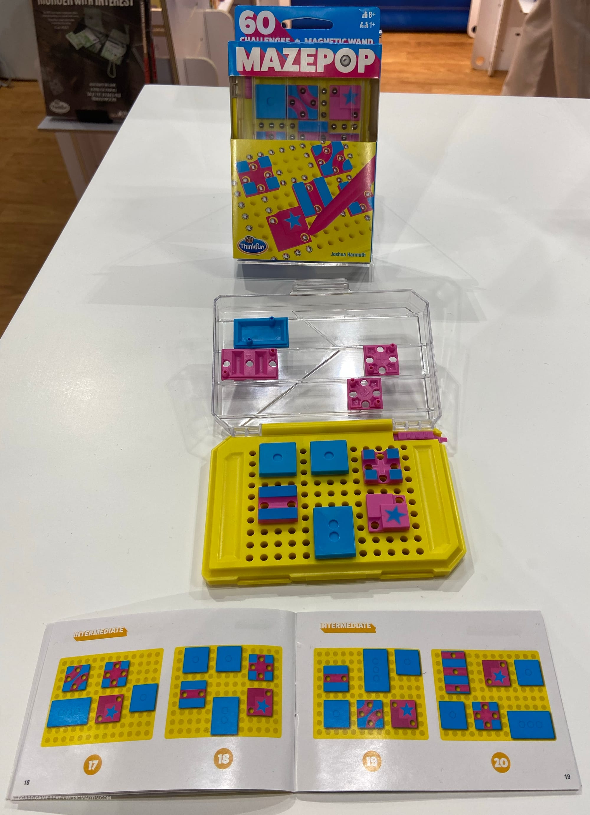 A plastic grid has dozens of holes in a rectangular grid, with pink and blue squares pushed into some of the holes to create an obstacle course