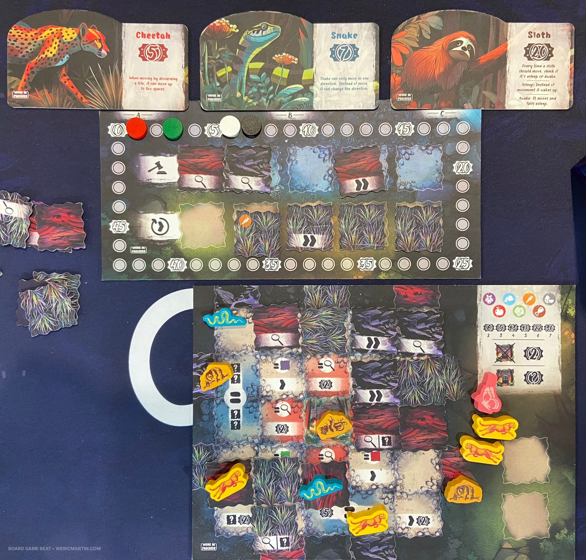 A tile drafting board is above a person's individual game board covered with tiles and wooden animals; three animal ID cards lie at the top of the image