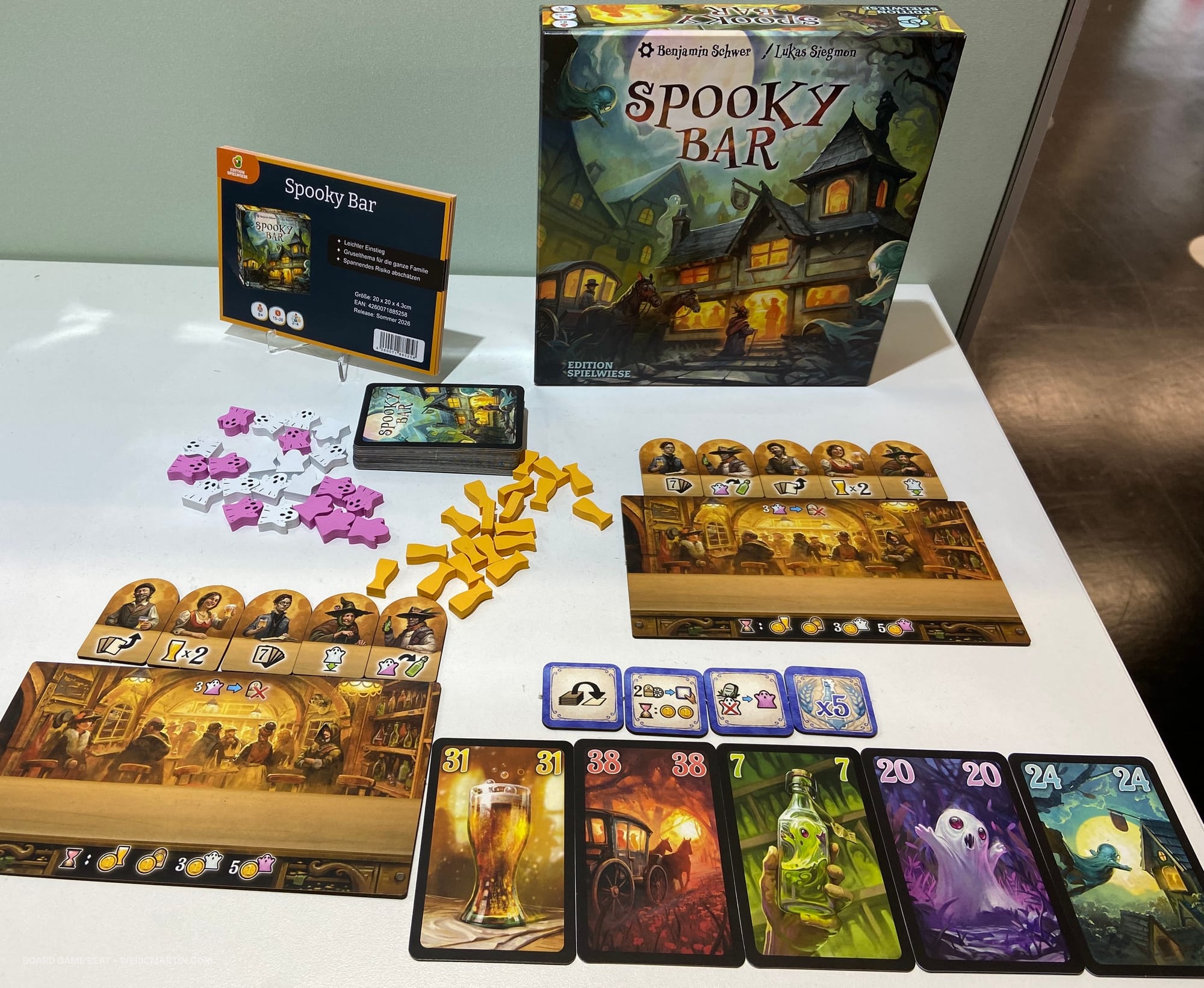 The front cover of Spooky Bar, with numbered cards in five colors in the foreground, along with customer tiles above two bars