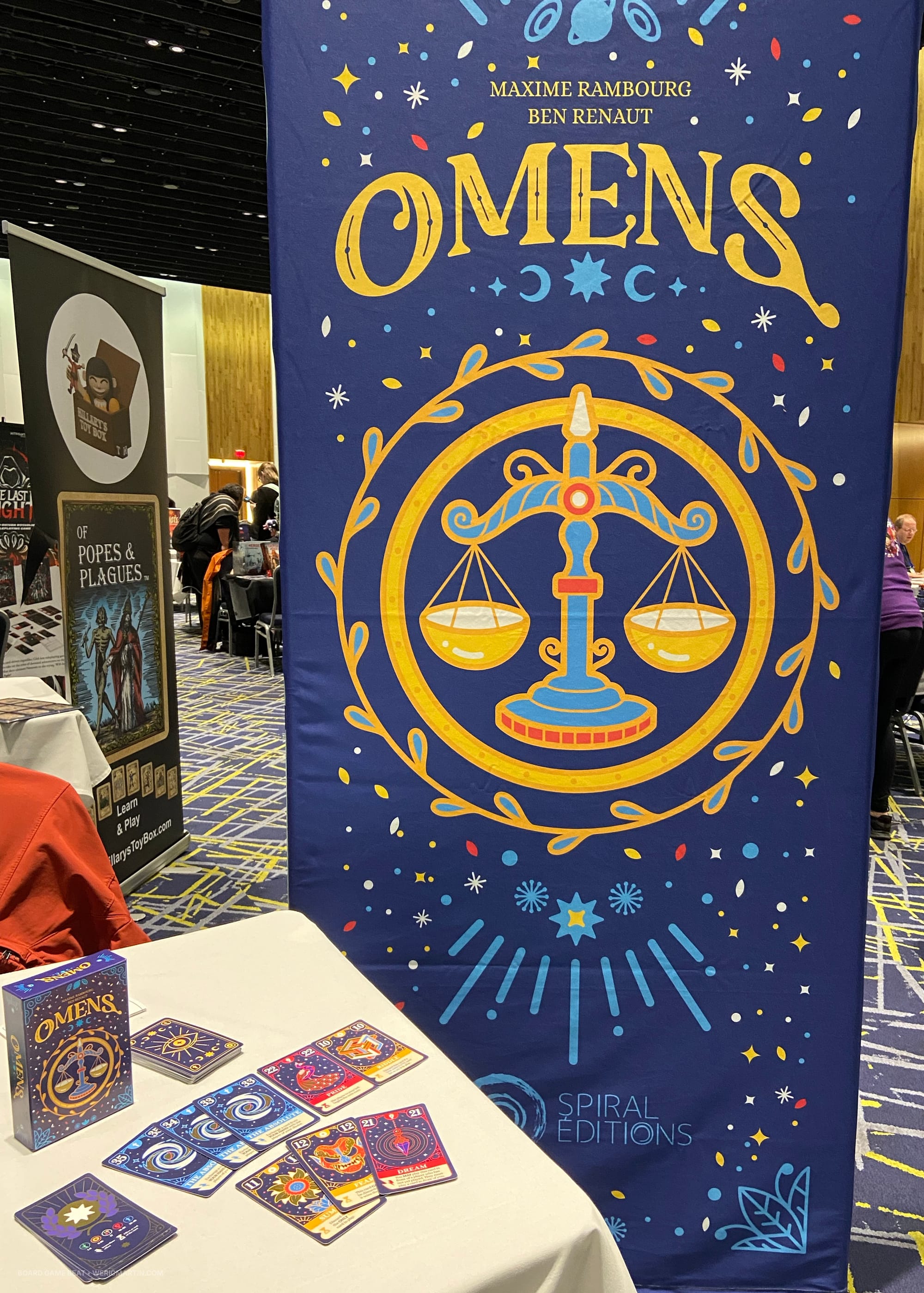 Banner for Omens, the English-language version of Présages, along with sample cards on the table