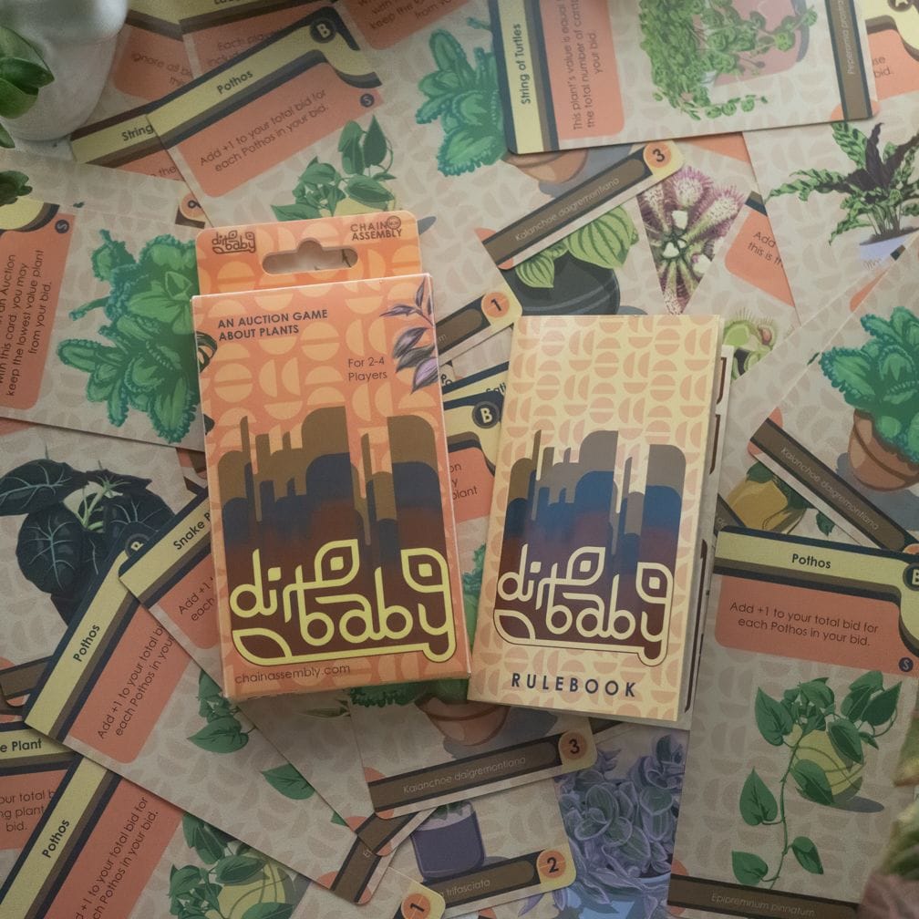 The box and rules for Dirt Baby, lying on top of cards in the game