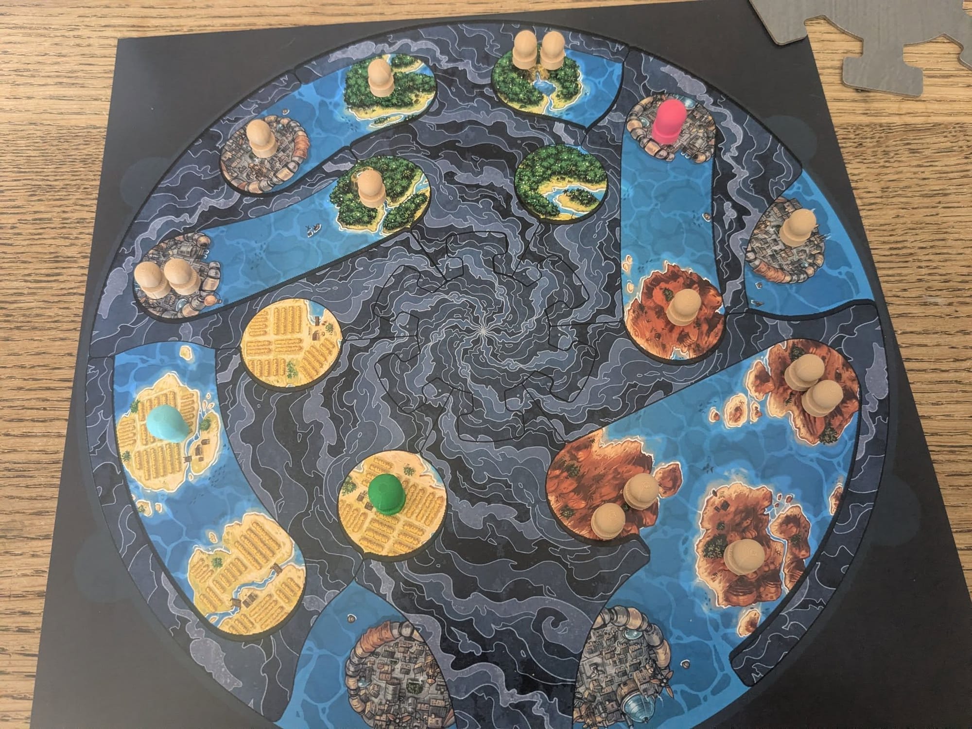 A circular game board has multiple tiles on it showing water and various types of landscape