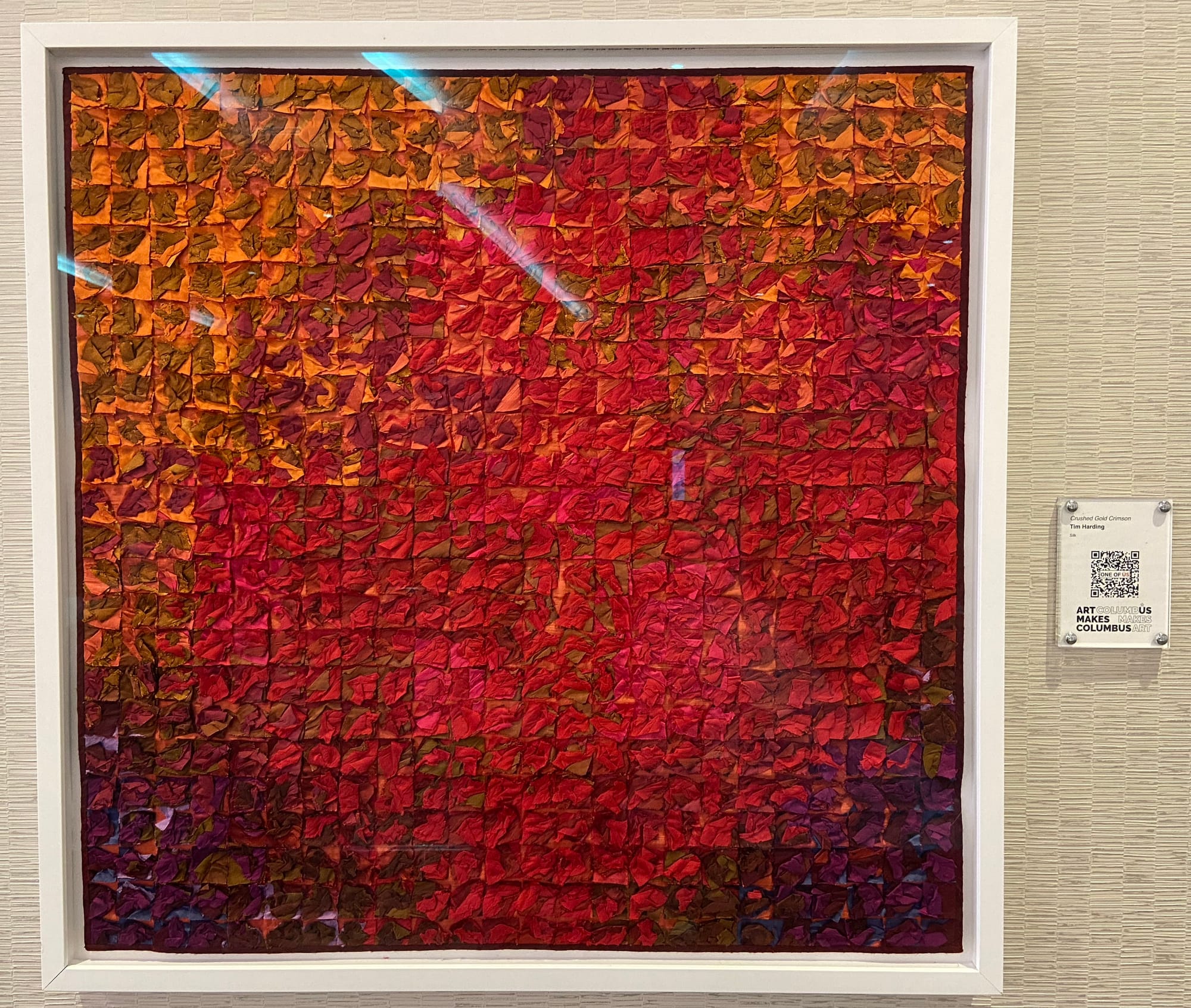 Tiny bits of silk are stacked into squares, with about thirty squares on a side, creating a flamelike image that transitions from purple to red to orange