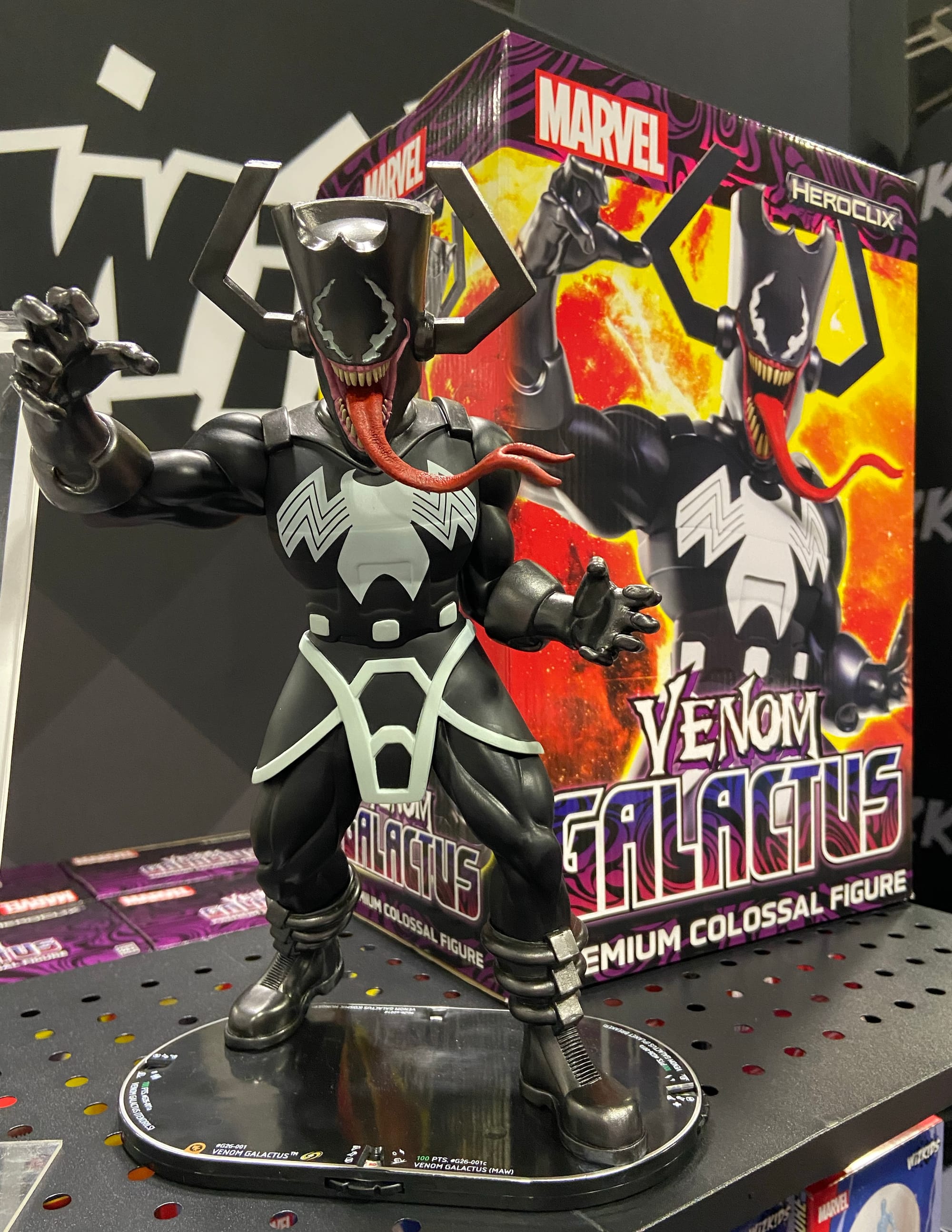 A Venom Galactus game figure is on a shelf in front of the box it comes packed in