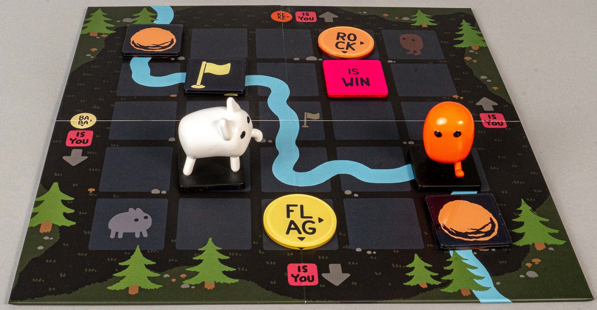 Two characters are on a 5x5 grid, along with word tiles, two rocks, and a flag.