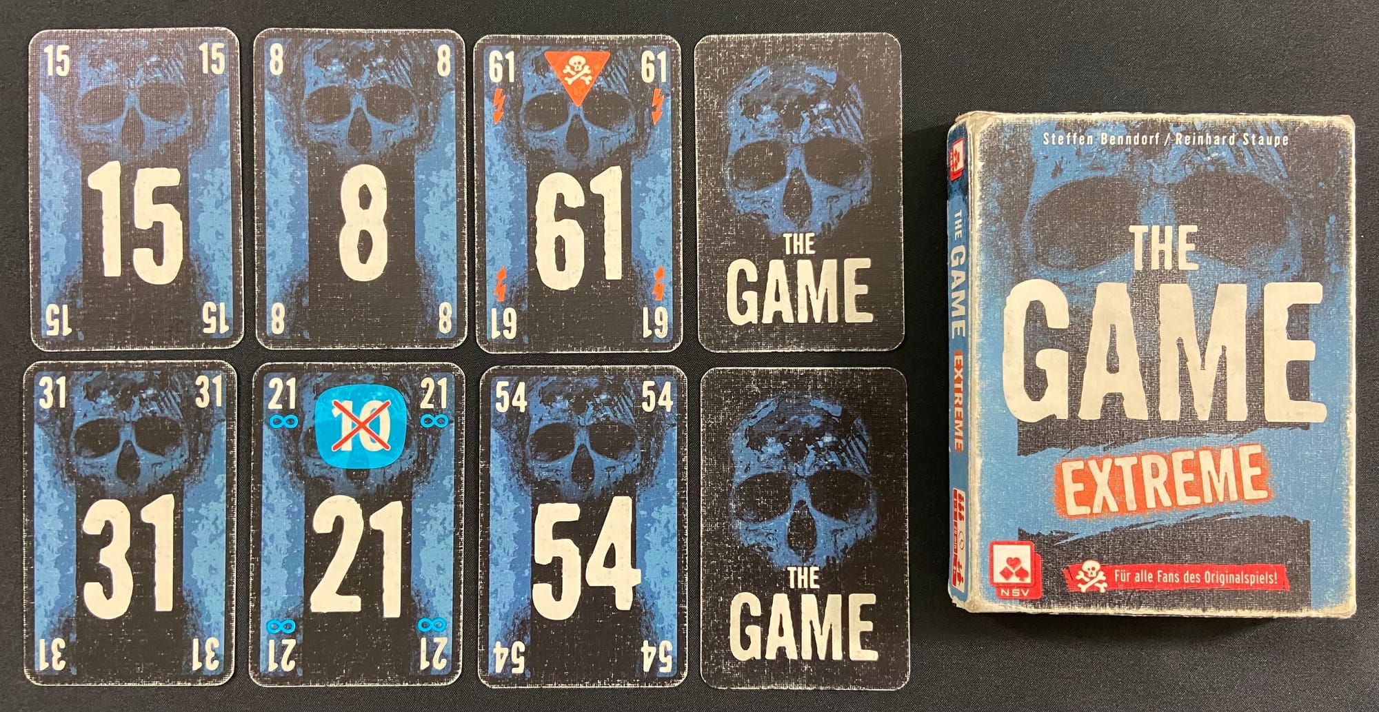 A heavily worn copy of The Game: Extreme beside its worn playing cards