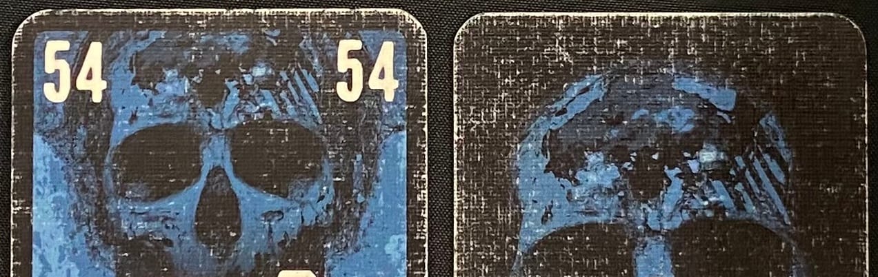 Close-up of the front and back of heavily worn The Game: Extreme cards